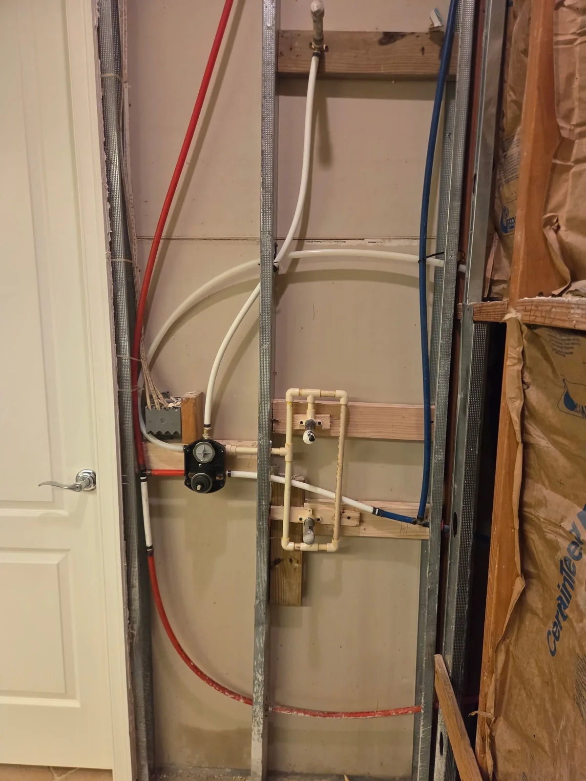 PEX water supply stub-outs and pressure regulator on a framed wall