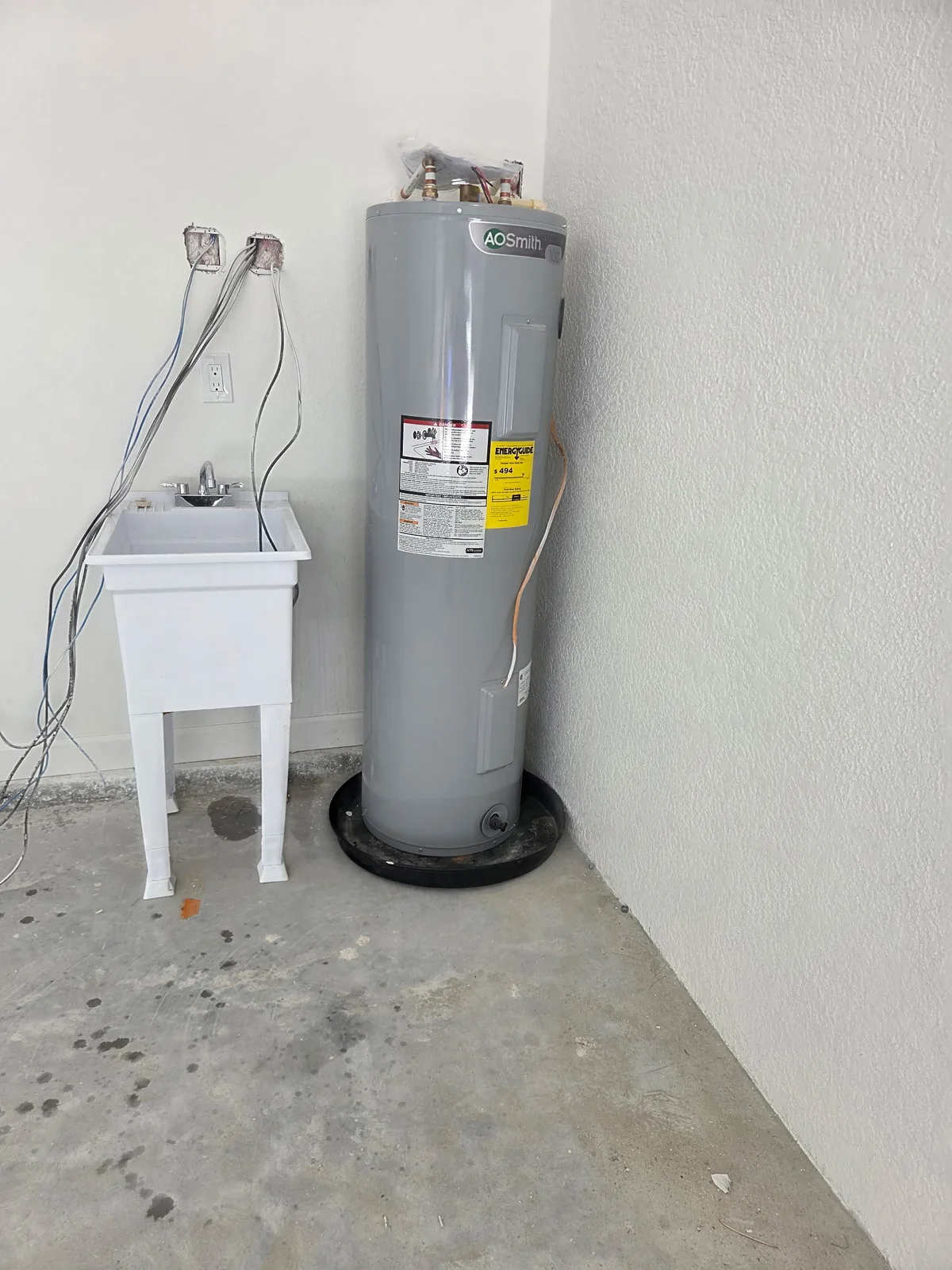 White utility sink and gray water heater installed in a garage