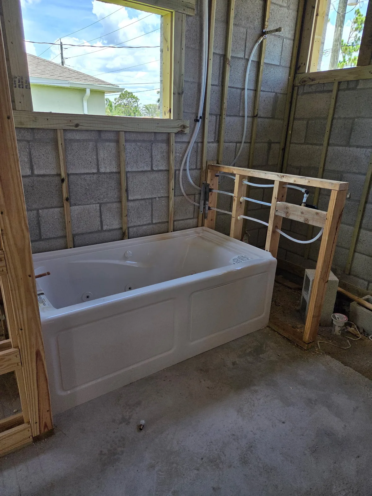 New bathtub set in a bathroom under construction with block walls and window