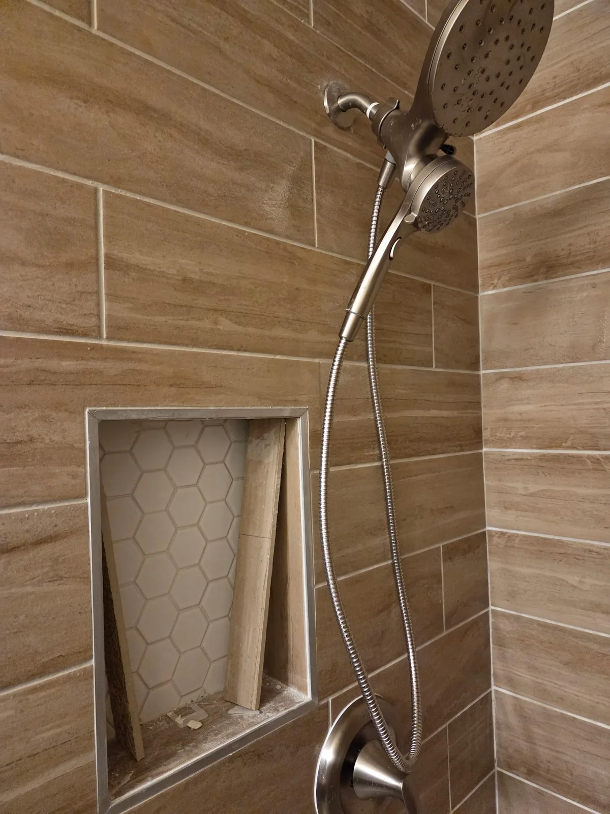 Finished tiled shower with wood-look tile, chrome rain shower head and niche