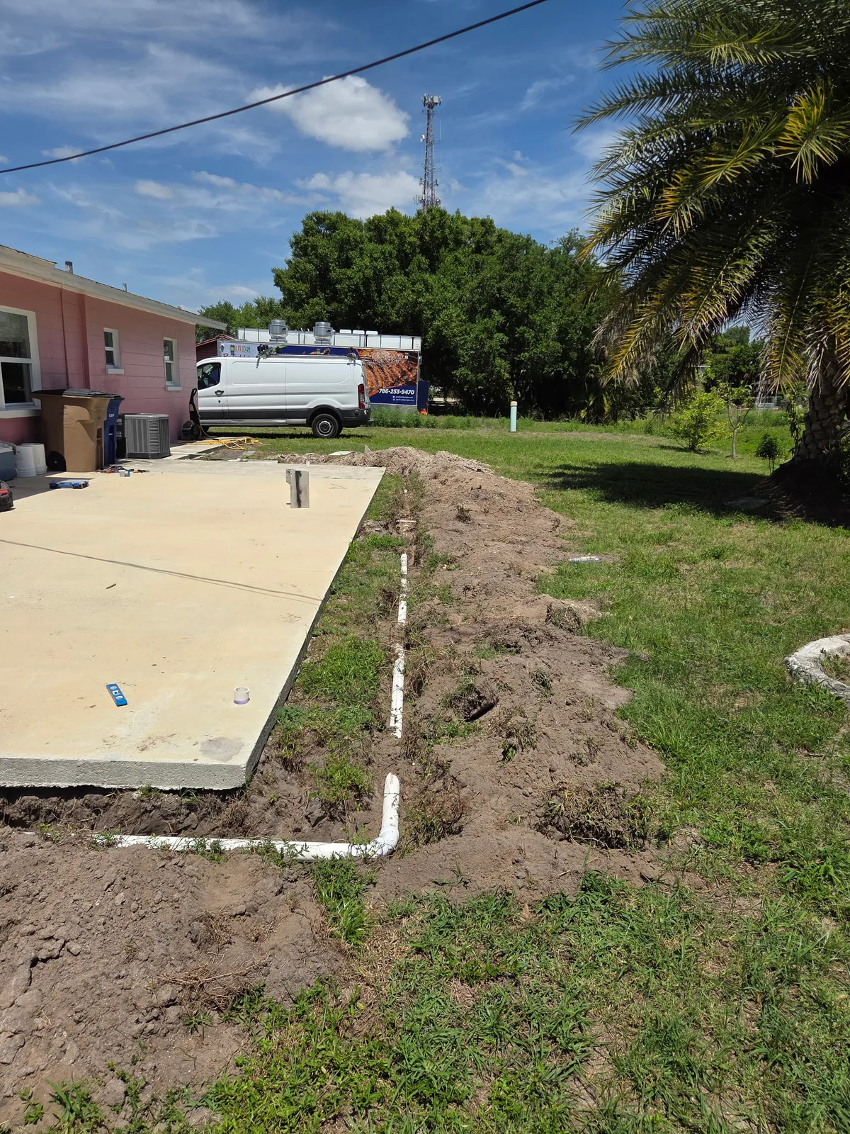 Fresh concrete slab poured on a residential lot with palm trees in the background