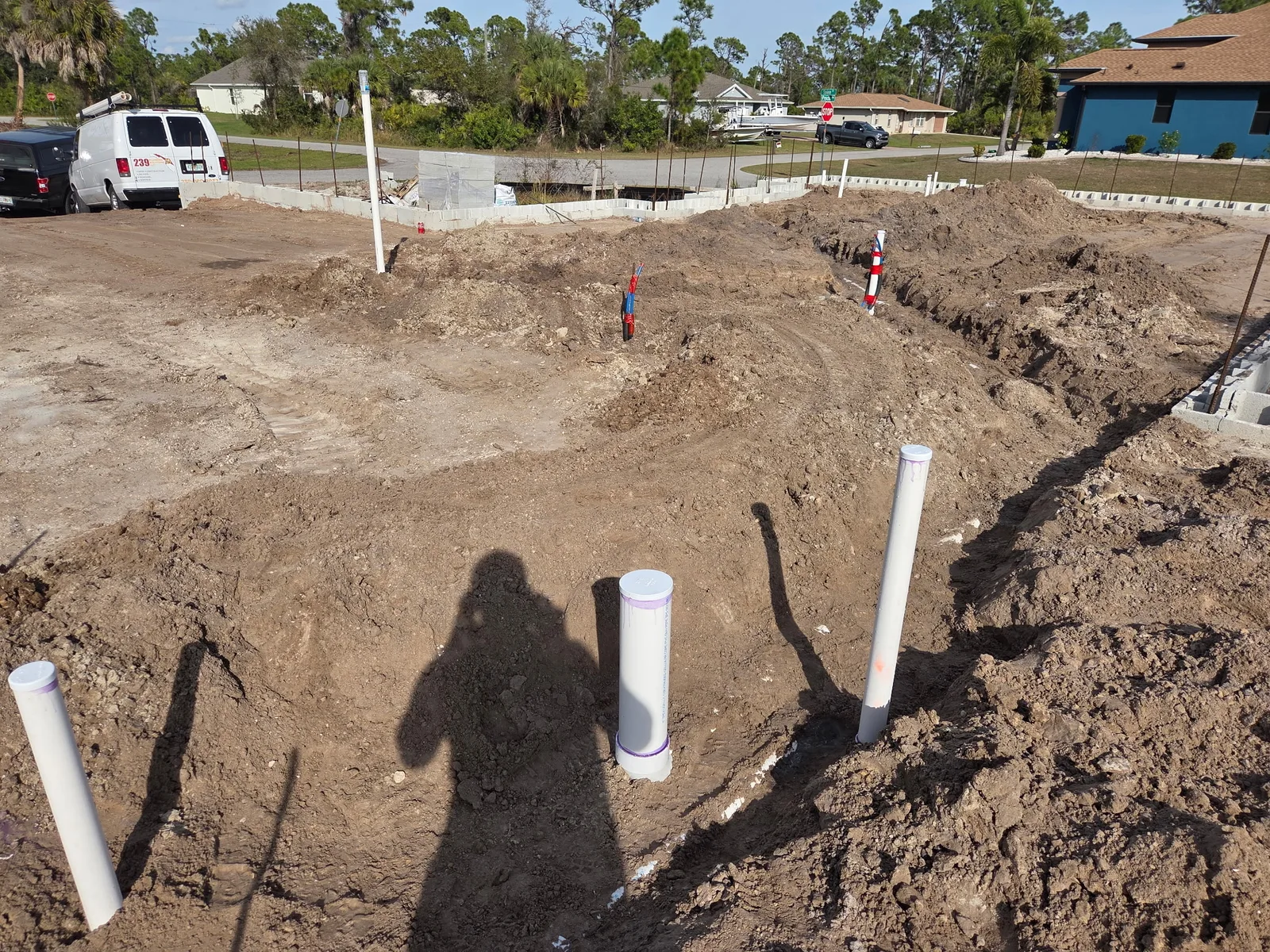 Graded dirt building pad with PVC plumbing stub-ups ready for a concrete slab